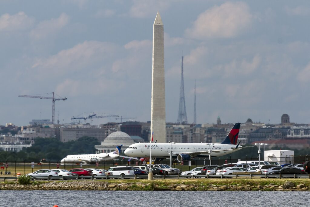 A Delta Air Lines plane sits on the tarmac at Washington National Airport, as the skyline of Washington, D.C. appears behind it, shimmering with heat. Recent air traffic control incidents at National and Newark International Airport have unnerved fliers.